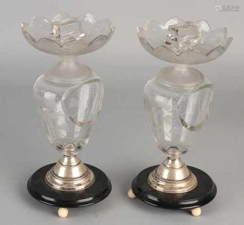 Two ornate crystal match holders with etched floral decoration placed on a round silver base, 833/