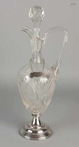 Crystal decanter with pouring range and ruitslijpsel placed on a round silver base on a roll.