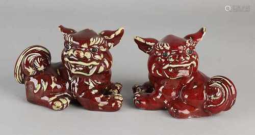 Two ancient Chinese porcelain Foo dogs with red enamel. 20th century. Noticed. Size: 10 x 15 x 9 cm.