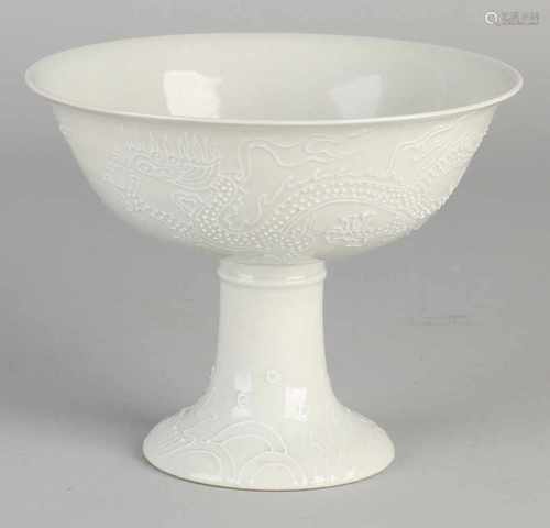 Chinese Blanc de Chine cup on high foot. Embossed dragons decor. One hairline. Dimensions: H 11 x