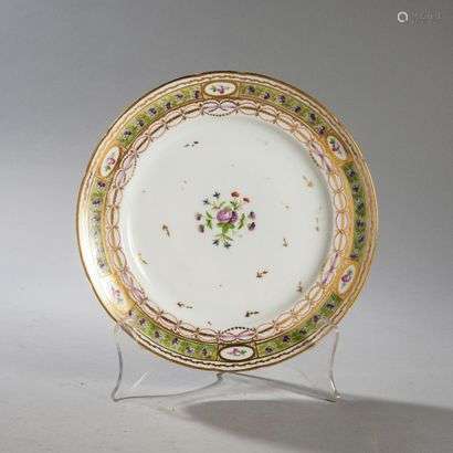 BORDEAUXPorcelain plate with contoured rim with polychrome decoration of a bouquet of flowers in the center and pansies and roses on a green background braid on the edge.Marked: W in gold.Manufacture of Verneuilh and Vanier.18th century. Diameter : 24,2 cm