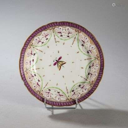 BORDEAUXPorcelain plate with polychrome decoration in the center of a butterfly and on the wing of foliage scrolls, butterflies and braid with purple background.Marked: W in gold.Manufacture of Verneuilh and Vanier.18th century. Diameter : 24.5 cm(A splinter)