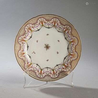 PARIS OR BRUSSELSPorcelain plate with contoured rim with gold decoration of flowers in the center and polychrome decoration on the wing of draperies, garlands and foliage scrolls.Marked: B in gold.End of the 18th century. Diameter : 24.4 cm