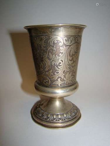 Silver cup. Foreign work, 19th century. The body swollen at the base rests on a pedestal chiselled with a frieze of eggs. It is engraved on a guilloche background with two large plain cartouches with matching mantling. One is stamped with a helmet with a crazy helmet face.Shocks. Import stamp (weevil).Height. 12 cm; Weight 89.4 g.