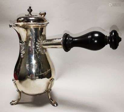 Silver chocolate maker. FRANCE, 18th century. Plain model standing on three feet. The decoration with double shell rockery, volutes and pine cone ending is confined to the base of the beak. The lid has a gadrooned border which is taken up by the disc sleeve. The thumb rest forms a scroll. The removable seed is button-operated. The handle is made of turned ebony. Opposite the handle, the belly is engraved with the monogram CM surmounted by a flowered crown. Traces of punches under the bottom. Lid not marked.Top. Width : 27 cm ; Width : 27 cm ; Net weight (without the handle) : 845,2 g.