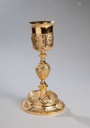 Silver gilt chalice. PARIS, silversmith J..., 1819-1838. Gilding redone and polished. Missing in the decoration of the false cup. Circular base decorated with cartouches of reeds alternating with heads of cherubs. The domed part of the foot is chiselled with symbols of the Passion (cross, pincers, nails ...), vine branches, ears of wheat alternating with three Amati medallions representing the theological virtues: Faith, Hope and Charity. The stem has an ovoid knot between two rings. The openwork false cup, with a fluted base, alternates vine branches, ears of wheat, reeds and three Amati medallions with representations of Jesus and the Virgin Mary. The decoration of vine branches is missing from the false cut.High. Diameter (section): 32.2 cm; Diameter (section): 9.7 cm; Diameter (foot): 17 cm; Weight: 744.9 g.