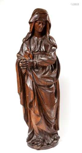 The Virgin on Calvary.Statue in the round made of oak wood,The full-length Virgin, her head covered with a veil, joins her hands on her left.Northern France, 17th century.Late dark varnish.High. : 92 cm