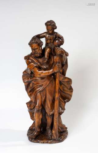 Saint Christopher carrying the Child Jesus. Lime wood statuette, The Child holding the orb sits on the left shoulder of the saint who holds a bumblebee in both hands. South Germany, early 17th century. H.46 cm.(Late varnish overlay)