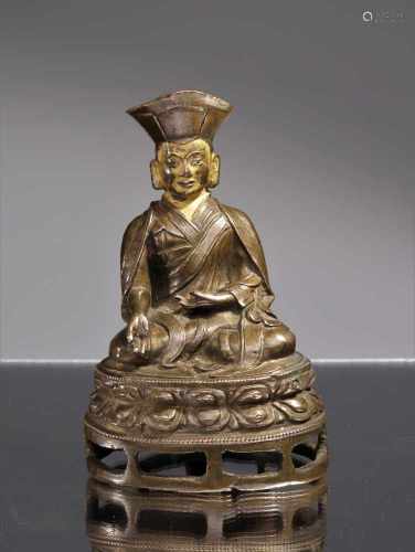 SITTING LAMA WITH INSCRIPTIONBronze with cold gilt faceTibet , 15th centuryDimensions: Height 11,5