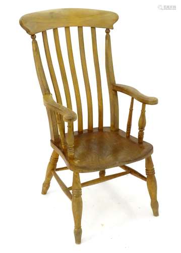 An early 20thC lathe back open armchair with an elm seat,