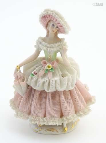 A Dresden porcelain figure of a lady wearing a porcelain lace dress and hat holding an umbrella.