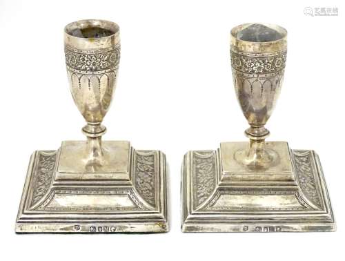 A pair of Victorian silver candlesticks with floral decoration.