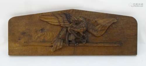 A carved oak plaque depicting an eagle with a snake grasped in its talons.