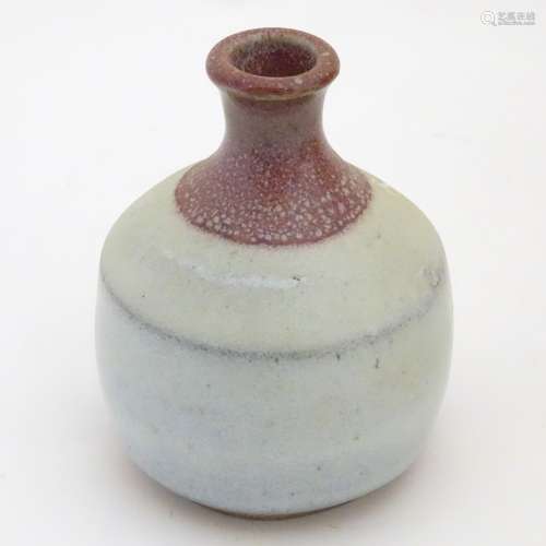 A small two-tone studio pottery bottle vase by Phil Rogers with an ash / nuka glaze.