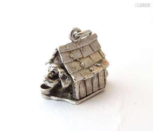 A novelty white metal charm formed as a dog in a dog kennel, hinging open .