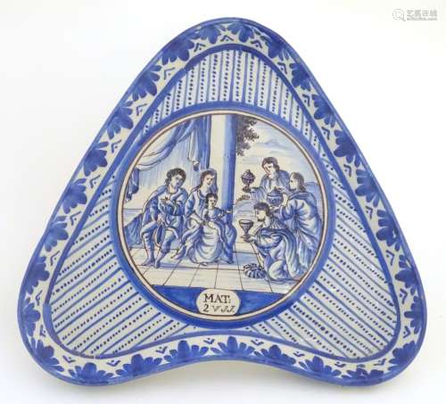 An 18thC blue and white Continental dish of triangular form raised on three feet.