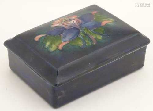 A 20thC W. Moorcroft lidded trinket box decorated with an iris flower on a blue ground.