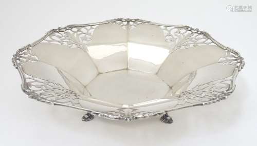 A large silver dish with fret work scroll decoration.