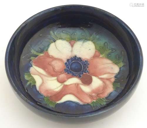 A 20thC Moorcroft circular dish decorated with an anemone flower on a blue ground. Marked under.