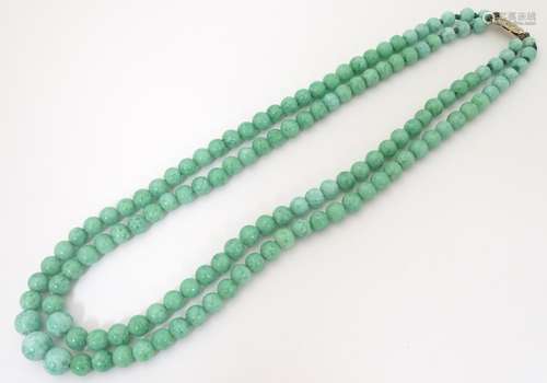 A vintage two-strand bead necklace if graduated jade green coloured beads with a silver gilt clasp.