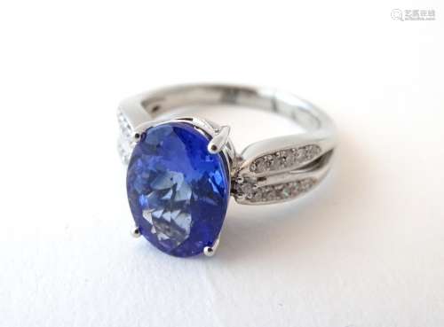 A platinum ring set with central blue iolite flanked by diamonds. Ring size approx.