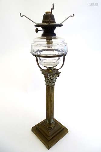 A late Victorian oil lamp, the clear glass reservoir supported by a brass corinthian column.