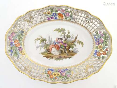 An oval basket dish with a reticulated floral border with gilt highlights,