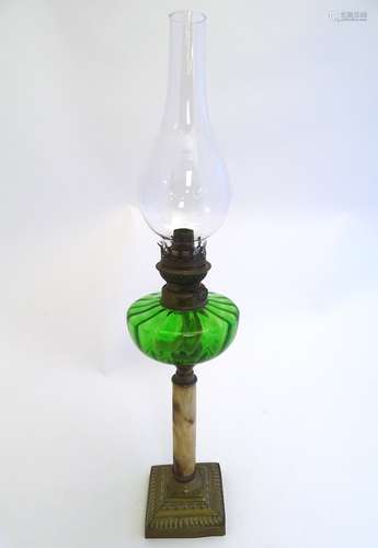 An early 20thC oil lamp, the green glass reservoir supported by an onyx and brass column and base,