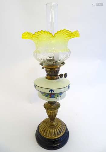 An early 20thC oil lamp, the frosted yellow glass shade with etched clear floral motifs,