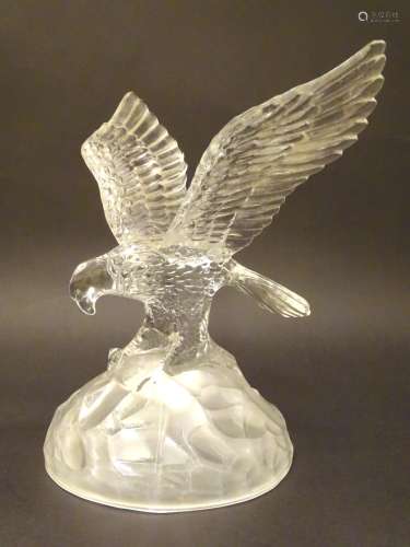 A 20thC glass figure formed as a landing eagle, clutching a salmon upon a domed frosted base.