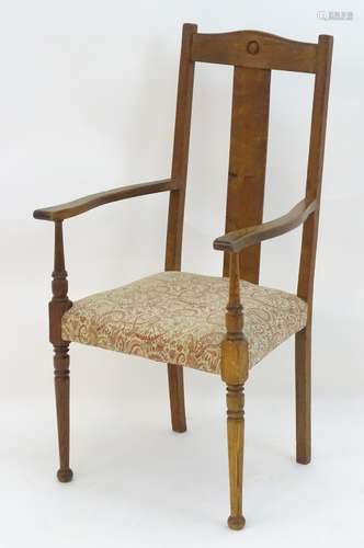 An early 20thC Arts & Crafts style open armchair with shaped top rail above a central rectangular