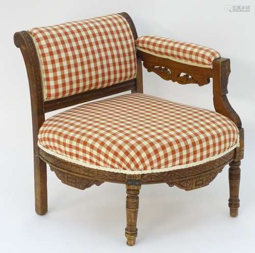 An early 20thC corner chair with a carved frame,