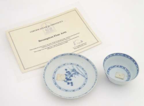 An 18thC Chinese Nanking Cargo blue and white tea bowl and saucer, decorated with pine trees.