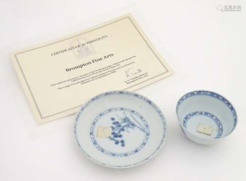 An 18thC Chinese Nanking Cargo blue and white tea bowl and saucer, decorated with pine trees.