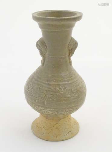 An Oriental earthenware vase with a flared base and rim, elephant head handles.