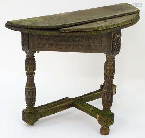 An antique credence table with a demi lune top and carved frame.