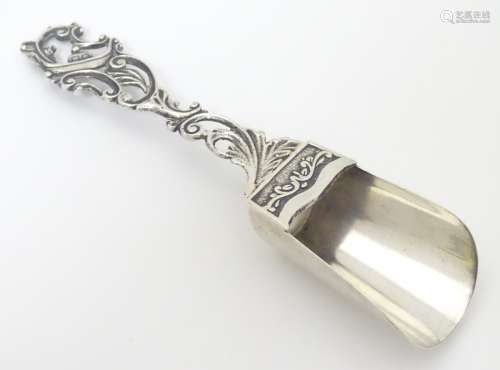 A Continental .800 silver caddy spoon with scroll decoration to handle.