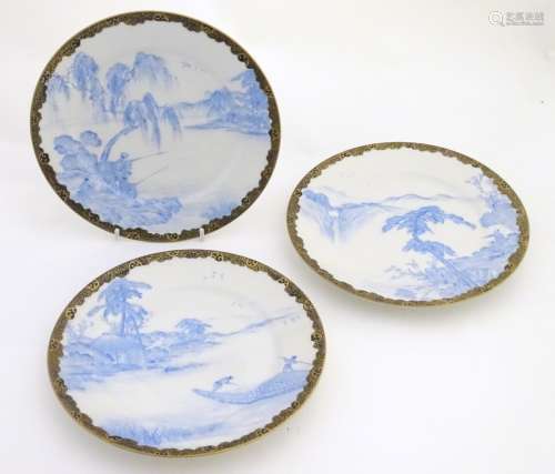 Three Japanese blue and white plates with landscape views and gilt patterned borders,