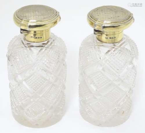 A pair of cut glass scent flasks / bottles with silver gilt tops with engine turned decoration.