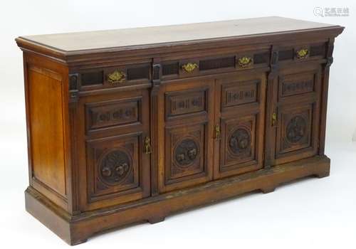 A Victorian walnut three drawer sideboard with pilaster decoration flanking and separating the four