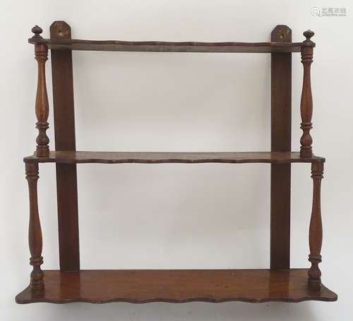 An early 20thC set of mahogany wall shelves with turned supports and three shaped tiers.