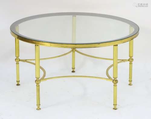 A mid 20thC glass top table with a brass base and star formed stretcher.