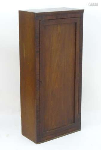 An early 20thC mahogany cupboard with a single panelled door opening to reveal fitted shelves