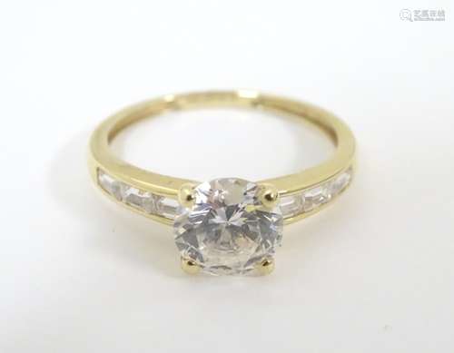 A 14 ct gold ring set with a large central cubic zirconia flanked by 3 baguette cut cubic zirconia