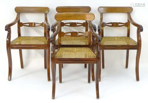 A set of four padouk wood open armchairs with curved top rails and carved mid rails above caned