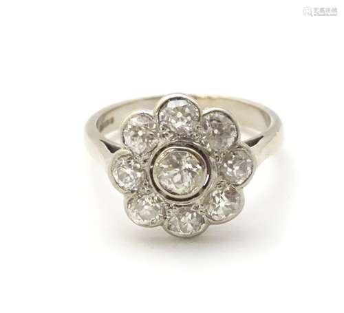 An 18ct white gold ring set with central old cut diamond bordered by 8 further diamonds in a daisy