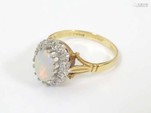An 18ct gold ring set with central opal bordered by diamonds. Ring size approx. P.
