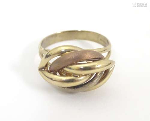 A 9ct gold ring with stylised three coloured gold knot decoration to top. Ring size approx. R 1/2.