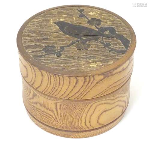 A 20thC cylindrical wooden box, with carved bird and blossom detail to top. Signed under E. Storey.