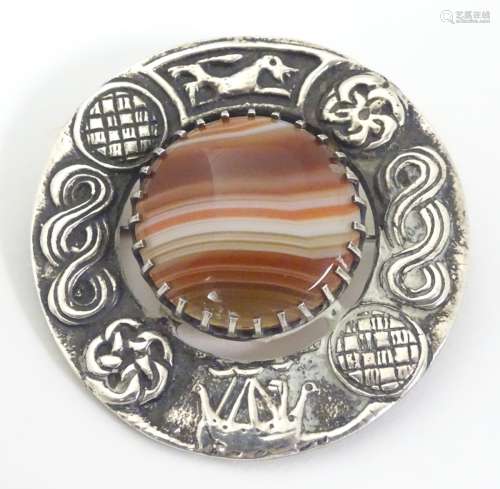 A Scottish silver brooch with central banded agate stone bordered by celtic inspired decoration.